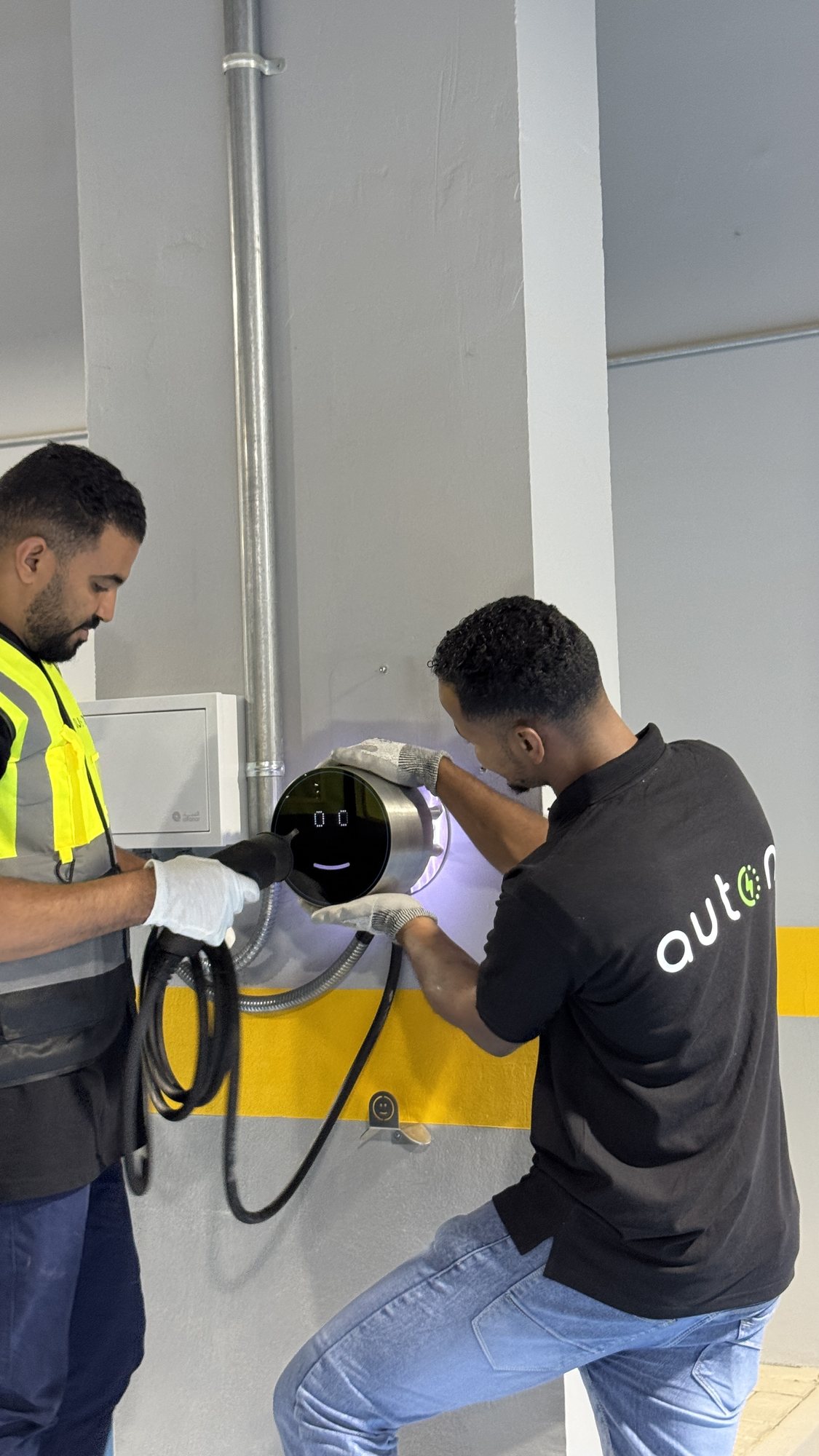 Auton installers fitting a wall charger in a car park